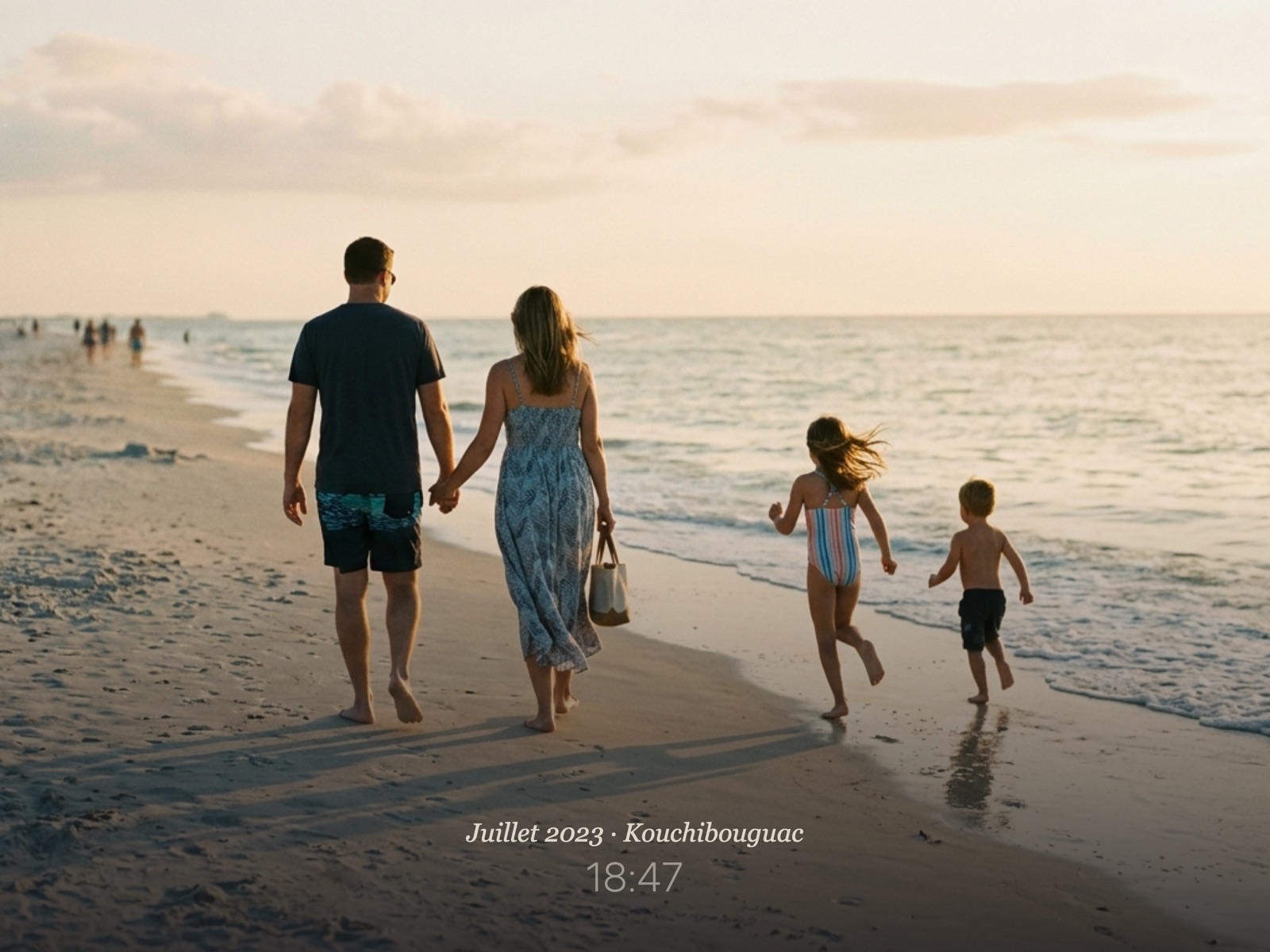 Une famille marchant sur la plage au soleil couchant, sur l'écran de Carrousel